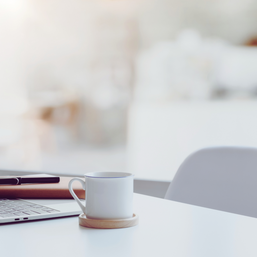 Laptop auf einem Schreibtisch mit einer Tasse Kaffee daneben